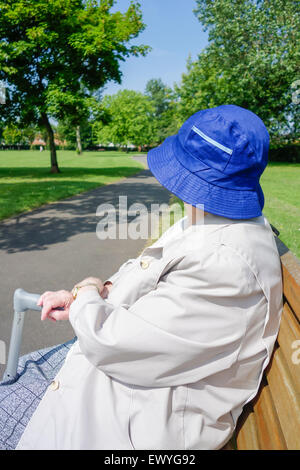 Dame in ihre neunziger Jahre auf Parkbank sitzen an einem sehr heißen Sommertag. England, UK Stockfoto