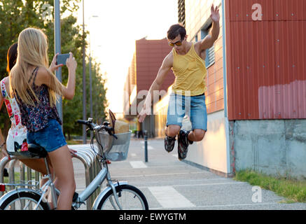 Outdoor Portrait junger Mann mit Rollschuhen springen und Mädchen fotografieren. Stockfoto