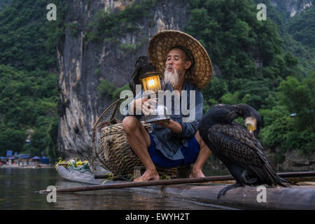 Kormoran Fischer auf einem Floß hält eine Laterne, Guilin, China Stockfoto