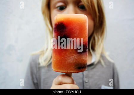 Junge hält einen gefrorenen Blackberry Eis am Stiel Stockfoto