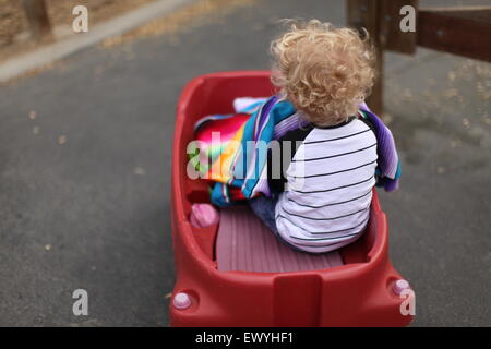 Rückansicht des ein Junge sitzt in einem Kunststoff Auto Stockfoto