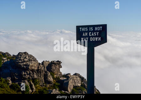 Melden Sie liest "dies keine einfache Möglichkeit nach unten am Rand der Tafelberg, Kapstadt, vor ein Teppich aus weißen Wolken" Stockfoto