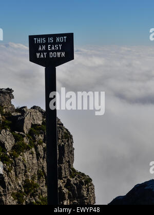 Melden Sie liest "dies keine einfache Möglichkeit nach unten am Rand der Tafelberg, Kapstadt, vor ein Teppich aus weißen Wolken" Stockfoto