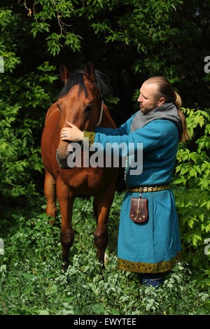 Mann, gekleidet in der Kleidung der Wikinger mit einem Pferd Stockfoto