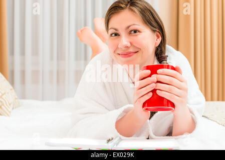 Mädchen in Bademantel Teetrinken im Bett ruhen Stockfoto