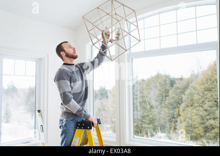 Junger Mann Installation Deckenleuchte Stockfoto