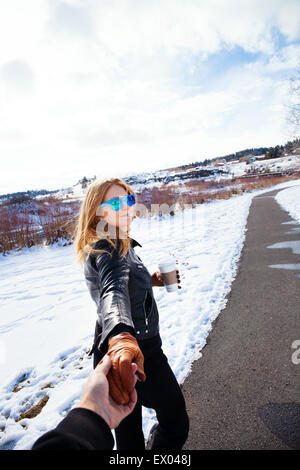 Frau mit Freunde Hand einen Spaziergang im Schnee bedeckte Landschaft Stockfoto