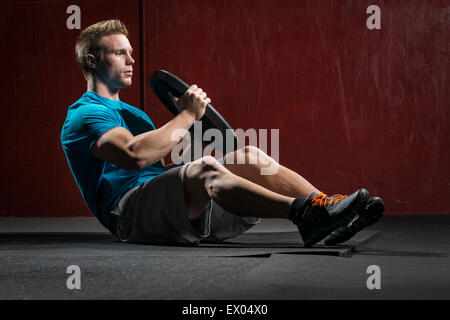 Mann hält Gewichtsplatte tun Sit Ups Stockfoto