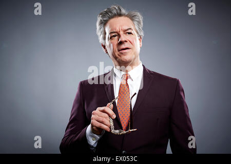 Studioportrait von reifer Geschäftsmann hält seine Brille Stockfoto