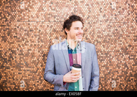 Junger Mann durch die Wand in Münzen Stockfoto