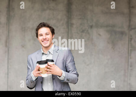 Geschäftsmann hält Einweg Kaffeetassen Stockfoto