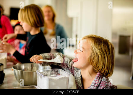 Junge Essen Puderzucker vom Spatel in Küche Stockfoto