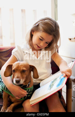 Mädchen-Lesebuch Hund auf Stuhl Stockfoto