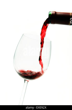 Rotwein aus der Flasche in ein Glas gegossen wird. Stockfoto