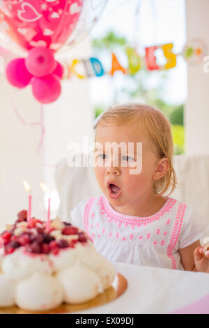 Kleines Mädchen bläst Kerzen auf ihrem Geburtstagskuchen Stockfoto