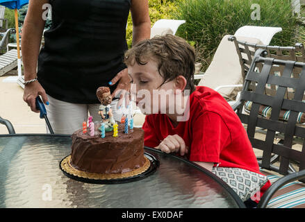 Boy bläst die Kerzen auf einem Geburtstagskuchen, geschmückt mit einem Fußball-Spieler-Figur. Stockfoto