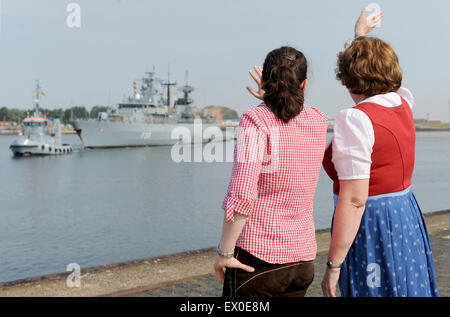 Wilhelmshaven, Deutschland. 3. Juli 2015. Die Fregatte "Bayern" kehrt nach einer 5-Monats-Mission vor der Küste Somalias zu seiner Heimatbasis in Wilhelmshaven, Deutschland, 3. Juli 2015. Eine Frau trägt Lederhosen und eine Frau trägt ein Dirndl erwarten seine Rückkehr. Die "Bayern" war vor allem in der Anti-Piraterie-Mission "Atalanta" beteiligt. Foto: INGO WAGNER/DPA/Alamy Live-Nachrichten Stockfoto