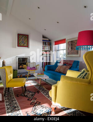 Kühnen blauen Sofa, Julep Stuhl und Eames Wire Schaukelstuhl im Wohnzimmer mit Aborigines Wandkunst und usbekischen Kelim Stockfoto