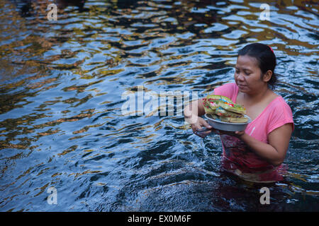 Eine Frau bringt religiöse Opfer im Schwimmbad des Tirta Empul Tempels in Tampaksiring, Gianyar, Bali, Indonesien. Stockfoto