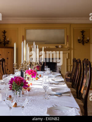 Kandelaber auf Esstisch mit weißer Baumwolle Tischdecke und Antik Esszimmerstühle Stockfoto