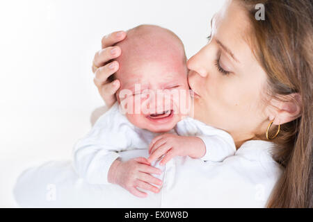 Junge Mutter, die ihr schreiendes neugeborenes Baby küssen Stockfoto