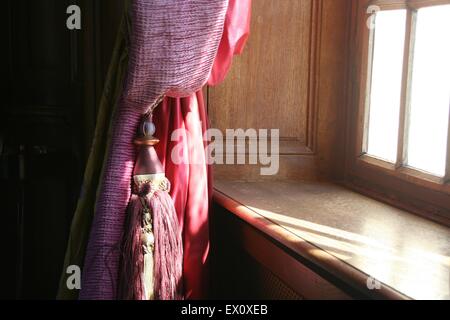 Elegante Quaste sanft hängend drapiert Vorhang Fenster, Frankreich. Stockfoto