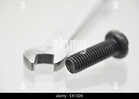 Schwarze Schrauben und Schraubenschlüssel auf grauem Hintergrund Stockfoto