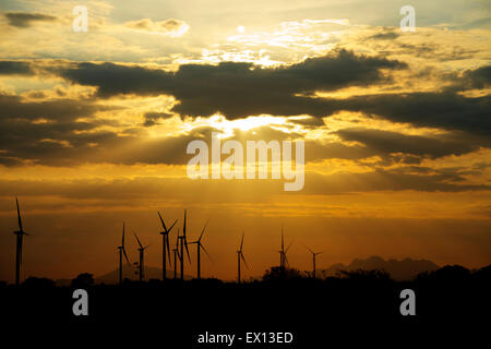 Windkraftanlagen als Silhouetten gegen einen wunderschönen Sonnenuntergang mit Sonnenstrahlen scheint herab Stockfoto