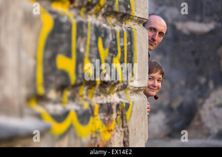 Paar, junge Familienglück. Ein Mann und eine Frau peering verschmitzt von der Ecke des Hauses. Stockfoto