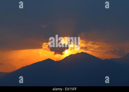 Sonne, spähen durch zerstreuen Gewitterwolken bei Sonnenuntergang über die Alpen Stockfoto