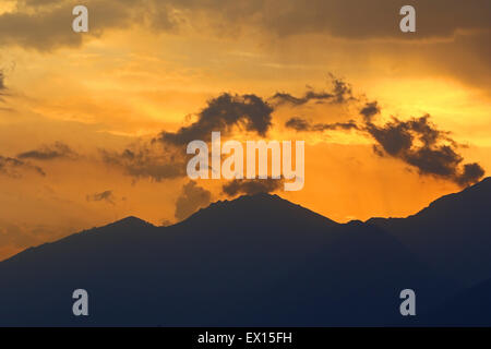 Sonne, spähen durch zerstreuen Gewitterwolken bei Sonnenuntergang über die Alpen Stockfoto