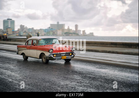 Havanna, Kuba - 13. Juni 2011: Old fashioned 50er Jahre Oldtimer geht vor der Skyline der Stadt entlang der Küstenstraße Malecón. Stockfoto