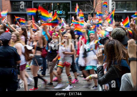 In NEW YORK CITY, USA - 28. Juni 2015: Stolz Zelebranten auf die jährliche Gay Parade Welle Regenbogenflaggen jubelnden Zuschauern vorbei. Stockfoto