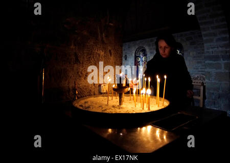 Eine griechische Verehrer Anzünden von Kerzen am Eingang der Kirche Kapelle Katholikon im griechisch-orthodoxen Kloster Heilige Varlaam gebaut im Jahre 1541 auf Natursandstein Felssäulen in Meteora am nordwestlichen Rand der Ebene von Thessalien nahe dem Fluss Pinios und Pindos Berge in Zentral-Griechenland Stockfoto