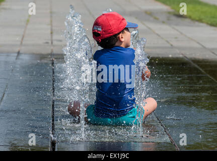 Berlin, Deutschland. 4. Juli 2015. Ein Junge kühlt in einem Brunnen in Berlin, Deutschland, 4. Juli 2015. Foto: Paul Zinken/Dpa/Alamy Live News Stockfoto