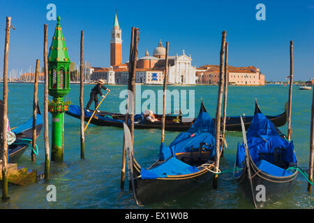 Gondelboote legen entlang des Markukanals in Venedig mit San Giorgio Maggiore und dem Markusturm in der Ferne, Italien, fest Stockfoto