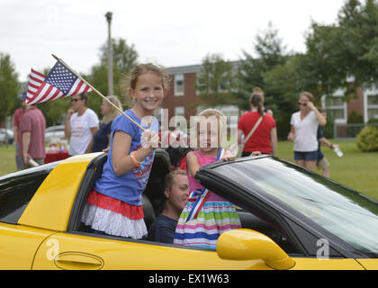 Wantagh, New York, USA. 4. Juli 2015. Zwei junge Mädchen, eine amerikanische Flagge halten und tragen eine rote weiße und blaue Schärpe, lächelnd stehen, wie sie in einem gelben Sportwagen in der Wantagh 4. Juli fahren Parade, eine langjährige Tradition der Unabhängigkeitstag auf Long Island. Bildnachweis: Ann Parry/ZUMA Draht/Alamy Live-Nachrichten Stockfoto