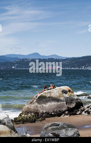 Mann, die Verlegung auf einem großen Felsen an einem sonnigen Tag im Stanley Park in Vancouver Stockfoto