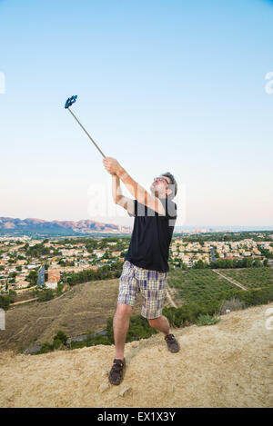 Kerl mit Selfie Stick versuchen, cool aussehen Stockfoto