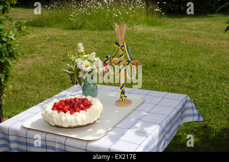 Tabelle in einem Garten mit einem neugebildeten Erdbeerkuchen, Mittsommer Pol und Blumen geschmückt Stockfoto