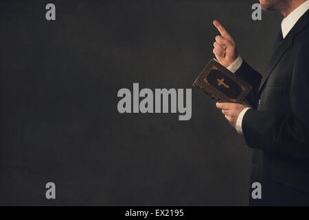 Ein stehender Mann in Anzug mit einer Bibel und erhobenem Zeigefinger Stockfoto