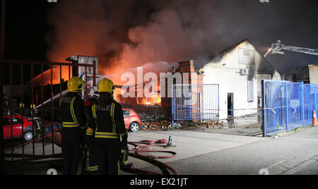 Perivale, West-London, UK. 4. Juli 2015. Ein Großbrand in einem Lagerhaus im Westen Londons erforderlich, mehr als 120 Feuerwehrleute unter Kontrolle zu bringen. Die Feuersbrunst im Wadsworth Road, Perivale, begann kurz vor 19:00 am Samstag. Wie Flammen durch die zweistöckige Gebäude, einen 50 m 20 m Struktur des gemischten Industrieanlagen, Riss waren Federn von dicken schwarzen Rauch sichtbar quer durch London. Etwa 30 Menschen wurden aus dem Lager evakuiert, aber es gibt keine Berichte über Verletzungen. Bildnachweis: Jason Kay/Alamy Live News Stockfoto