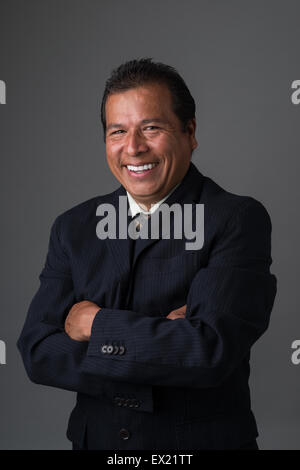 Hispano-Amerikaner Geschäftsmann lächelnd mit verschränkten Armen in einem Business-Anzug posieren für ein Porträt Stockfoto