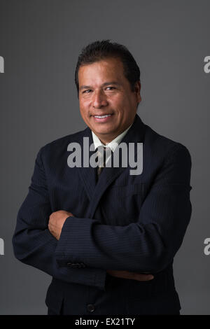 Hispano-Amerikaner Geschäftsmann lächelnd mit verschränkten Armen in einem Business-Anzug posieren für ein Porträt Stockfoto