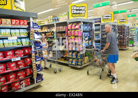 Mann mittleren Alters schiebt Supermarktwagen, Innenraum eines australischen Woolworths Supermarkt in Sydney, NSW, Australien Stockfoto