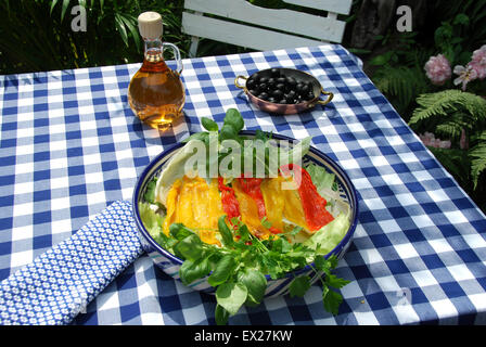 Paprika gebraten Satz in einer Schüssel mit schwarzen Oliven und einer Flasche des Verbandes. Stockfoto