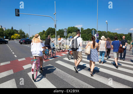 Fußgänger und Radfahrer, die beim Überqueren der Straße in Warschau, Polen Stockfoto