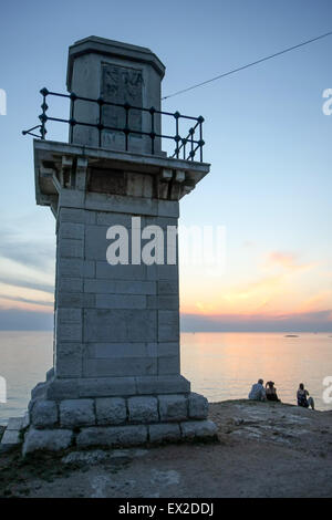 Touristen, der Leuchtturm am Ufer sitzen und den Sonnenuntergang in Rovinj, Kroatien. Stockfoto