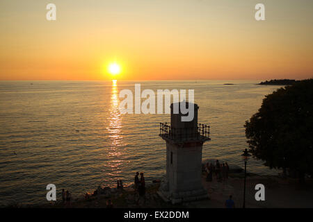 Eine Gruppe von Touristen durch den Leuchtturm am Ufer stehen und den Sonnenuntergang auf in Rovinj, Kroatien. Stockfoto