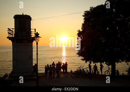 Eine Gruppe von Touristen durch den Leuchtturm am Ufer stehen und den Sonnenuntergang in Rovinj, Kroatien. Stockfoto